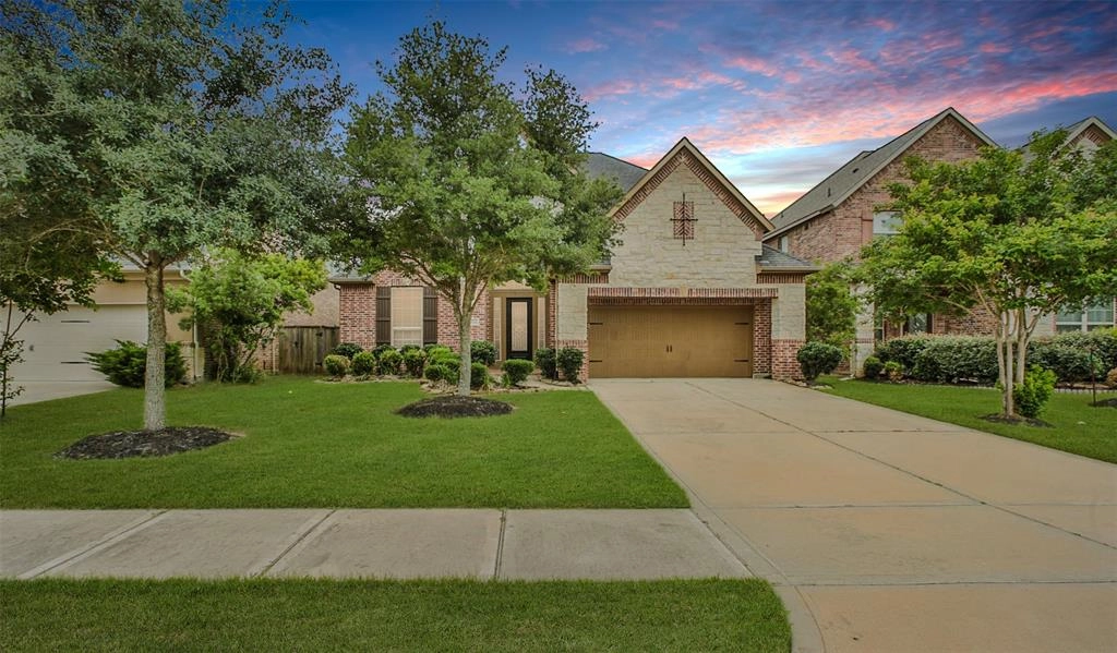 A large driveway with grass and trees in front of it.