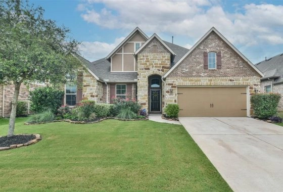A large brick home with a driveway and lawn.