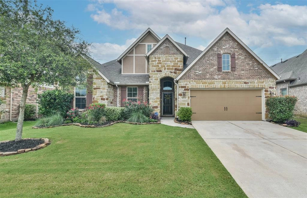 A large brick home with a driveway and lawn.