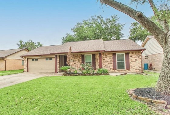 A brick house with a green lawn and trees.