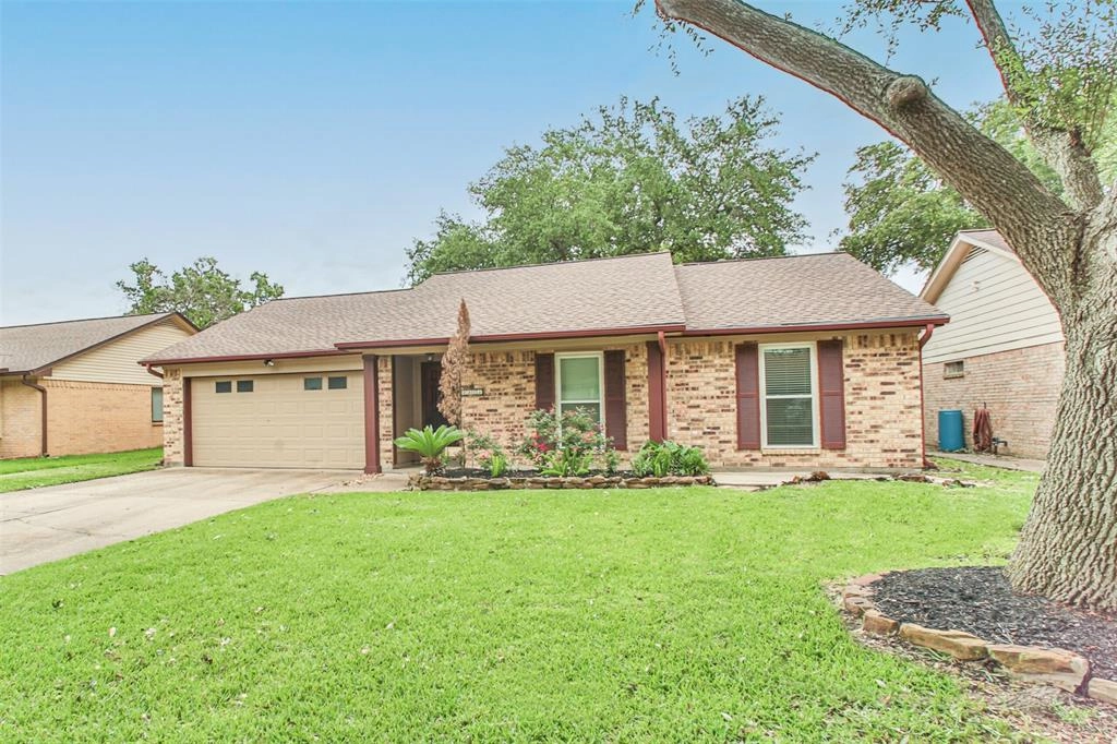 A brick house with a green lawn and trees.