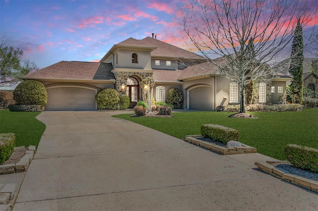 A large house with a driveway and lawn.