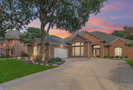 A large brick house with a driveway and trees.