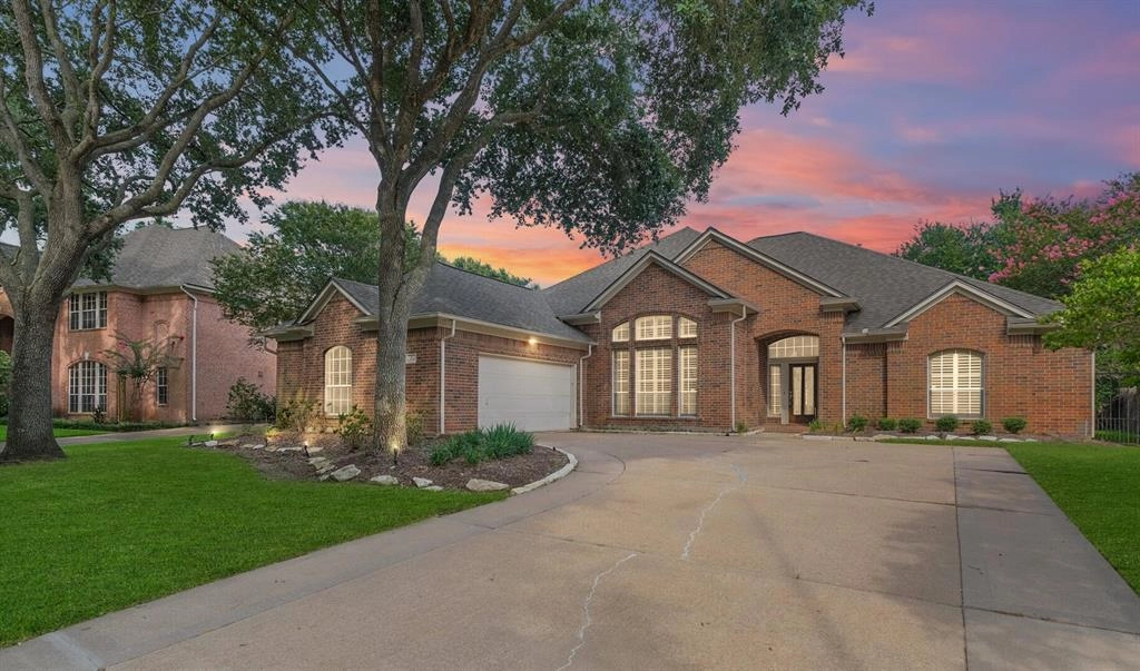 A large brick house with a driveway and trees.