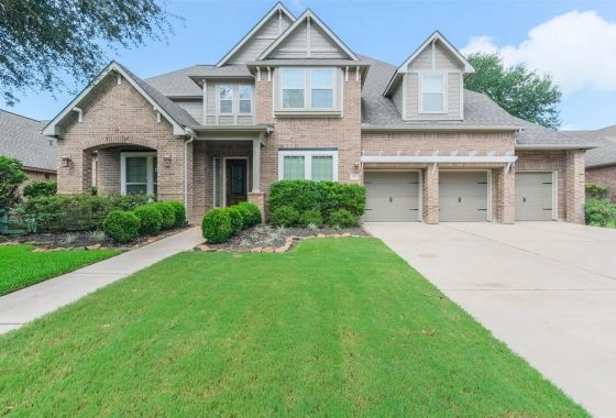 A large brick house with two garages and a lawn.