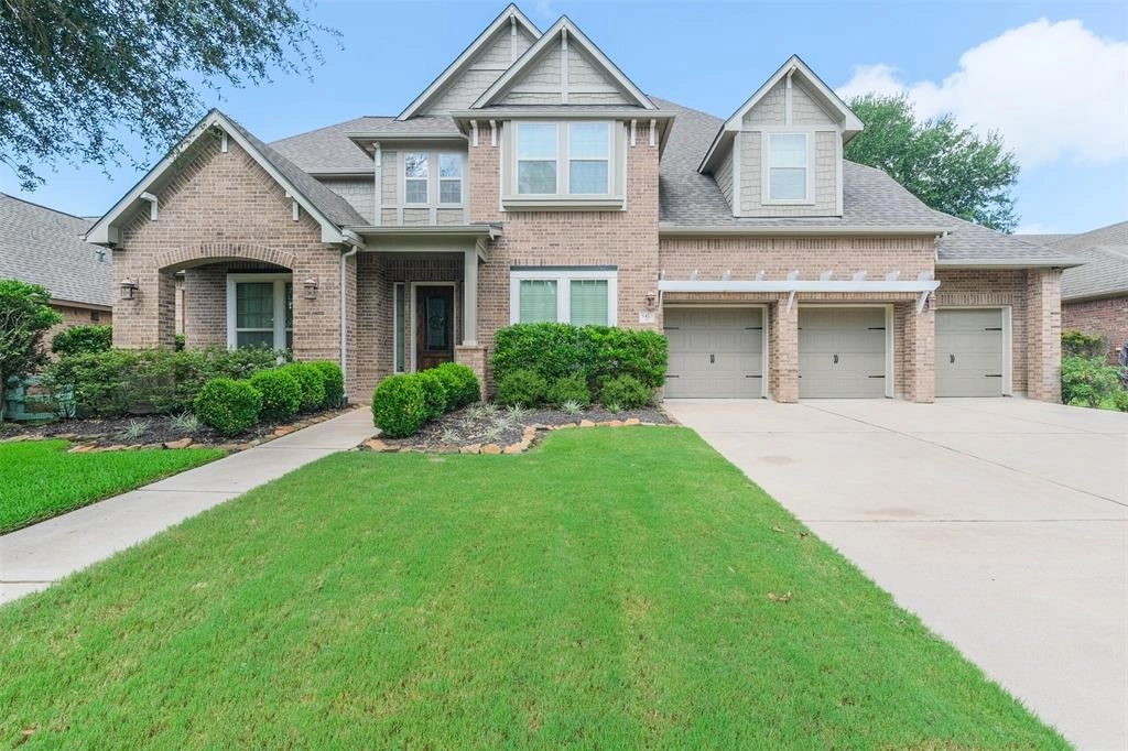 A large brick house with two garages and a lawn.