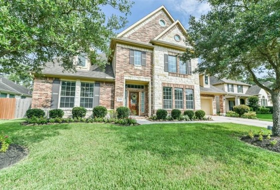 A large brick home with green grass in front of it.