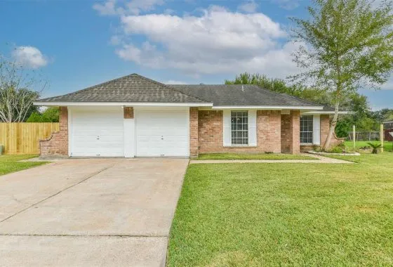 A house with two garage doors and grass in front of it.