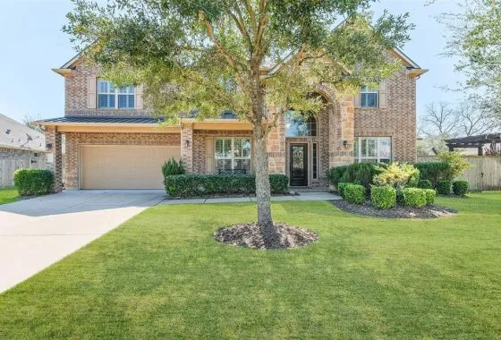 A large brick home with a tree in the front yard.