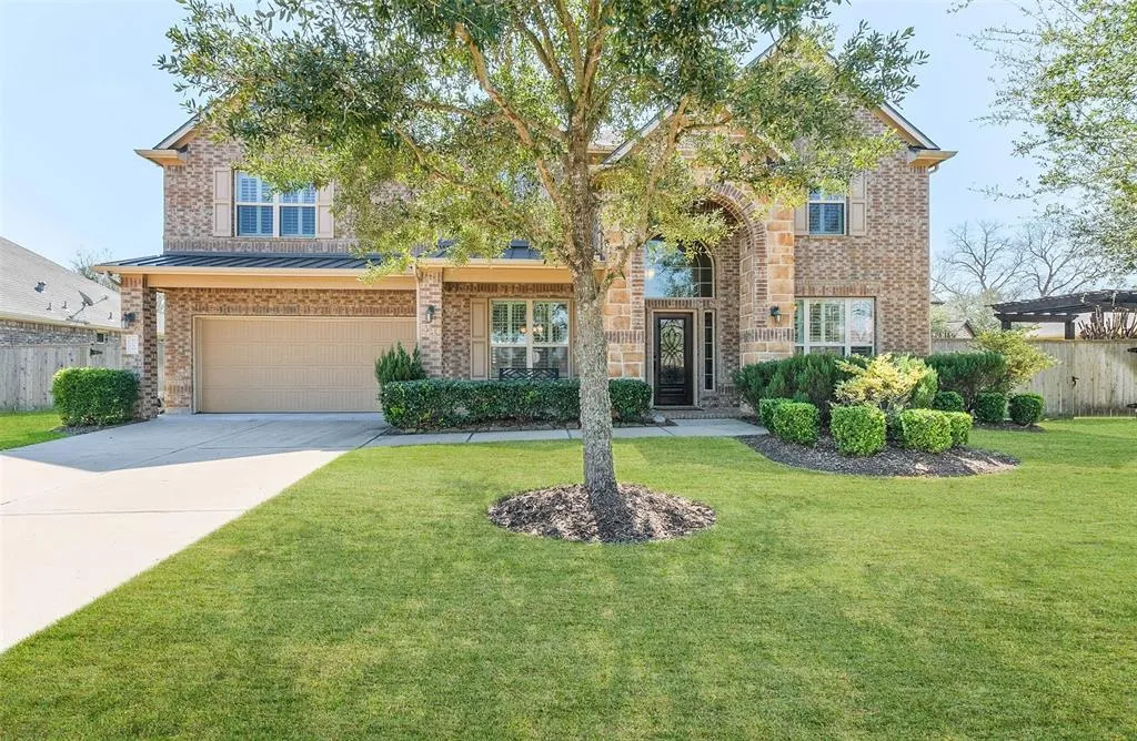 A large brick home with a tree in the front yard.