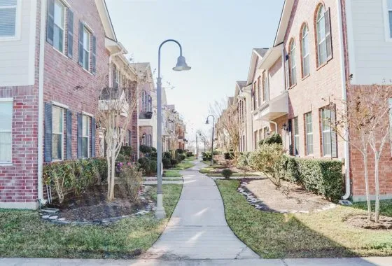 A sidewalk with grass and bushes in the middle of it.