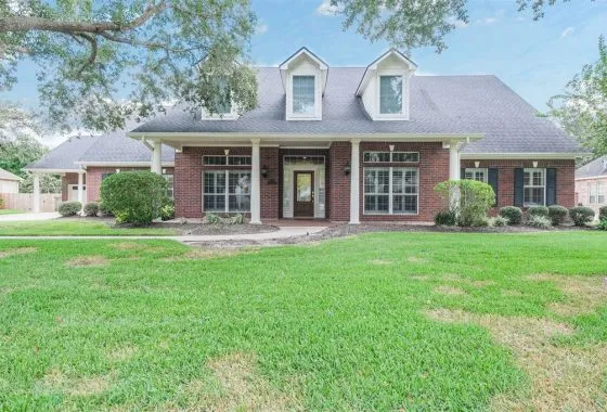 A large brick house with green grass in front of it.