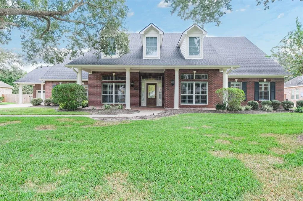 A large brick house with green grass in front of it.