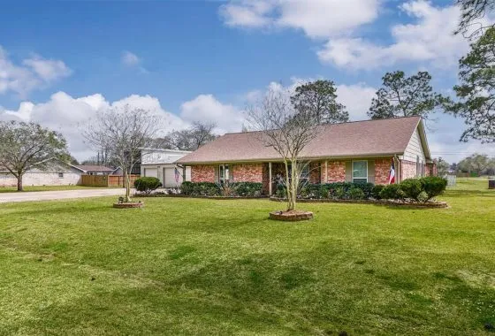 A large yard with grass and trees in front of it.