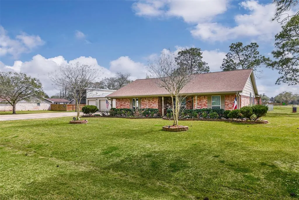 A large yard with grass and trees in front of it.