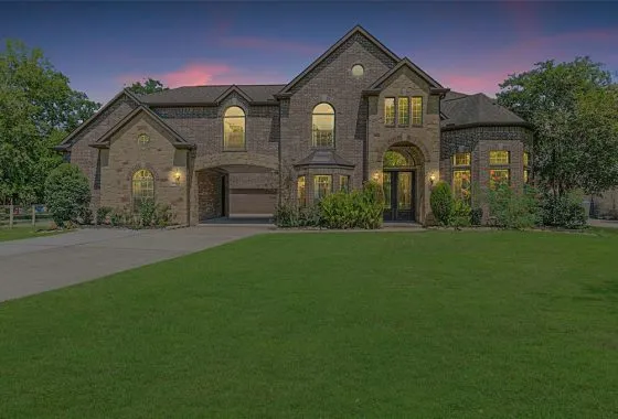 A large brick home with a green lawn in front of it.