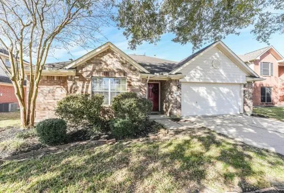 A house with a large driveway and trees in front of it.