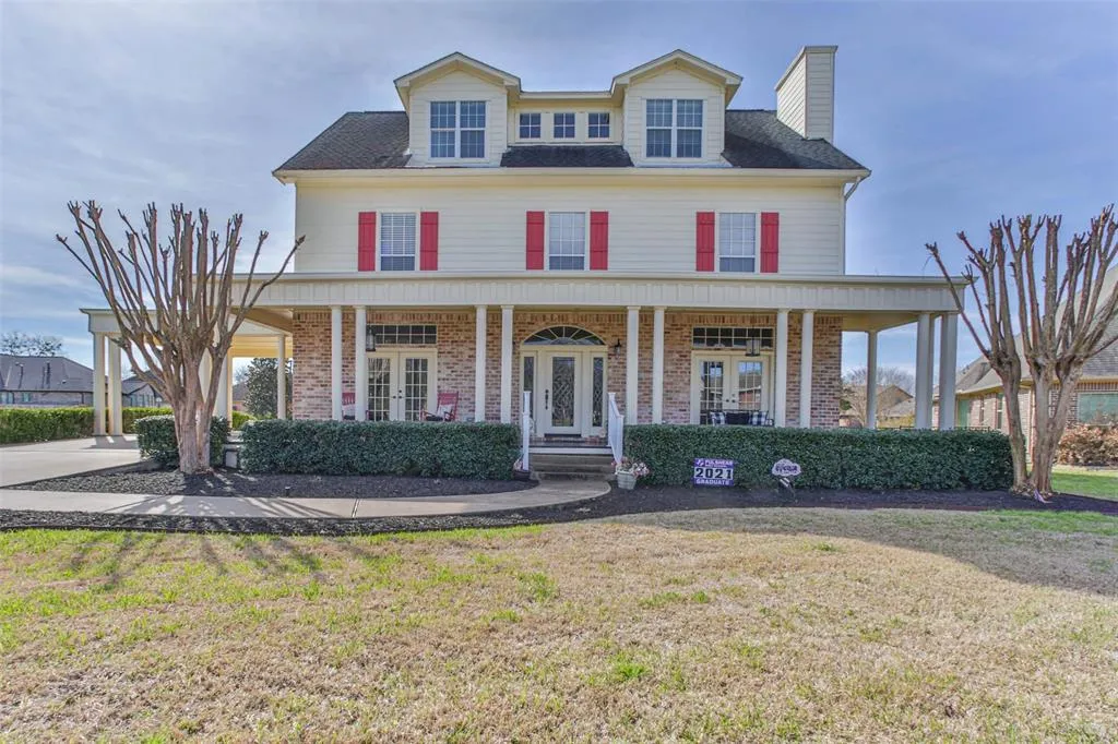 A large white house with red shutters and a porch.