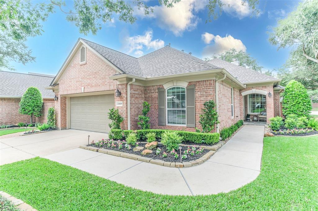 A large brick home with a driveway and landscaping.