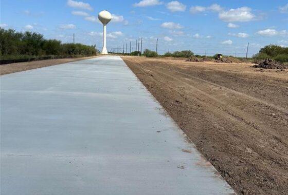 A road with no asphalt and a water tower in the background.