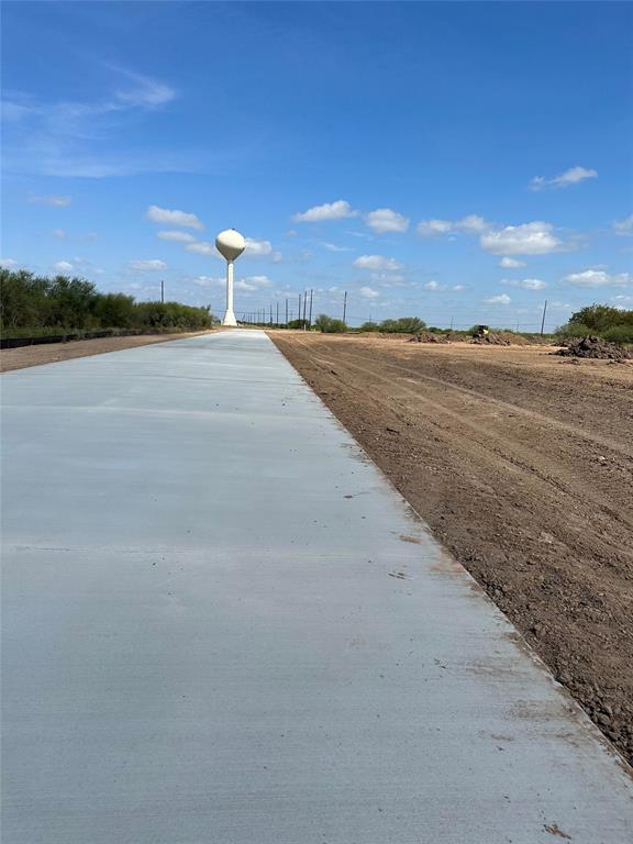 A road with no asphalt and a water tower in the background.
